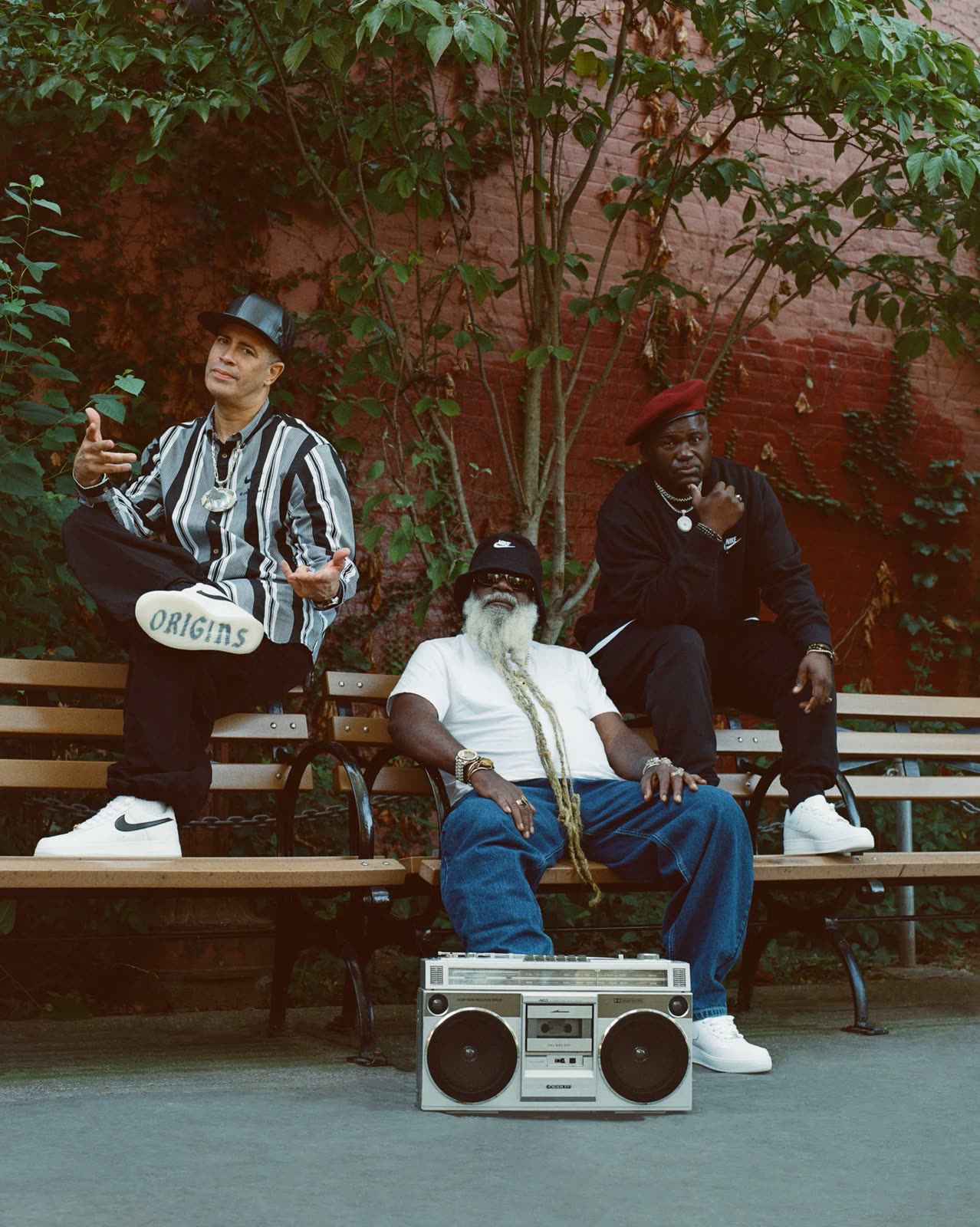 Three older men on park benches with a boombox; one Air Force 1 sole reads Origins