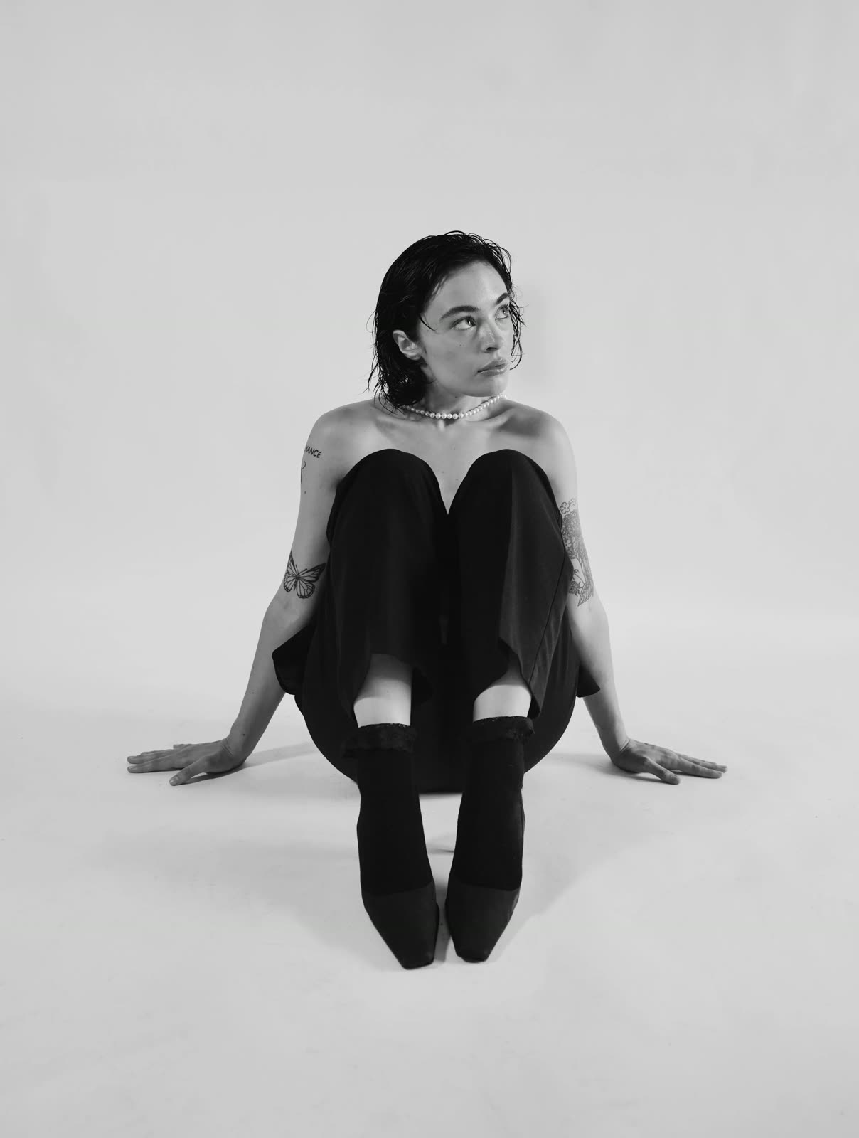 Black and white: Reilly Hail sits on the floor in a black strapless top, black trousers and pearls