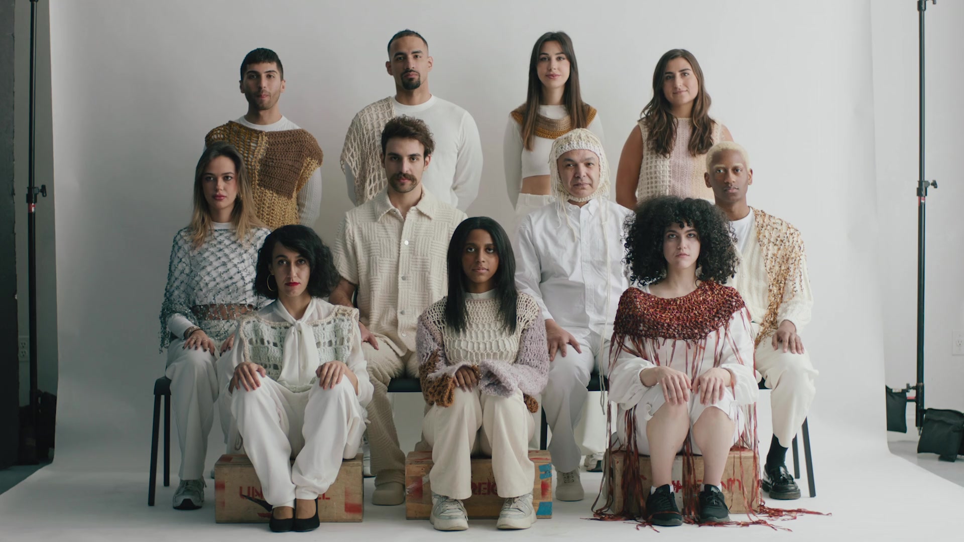 The cast in cream knitwear, seated in the studio