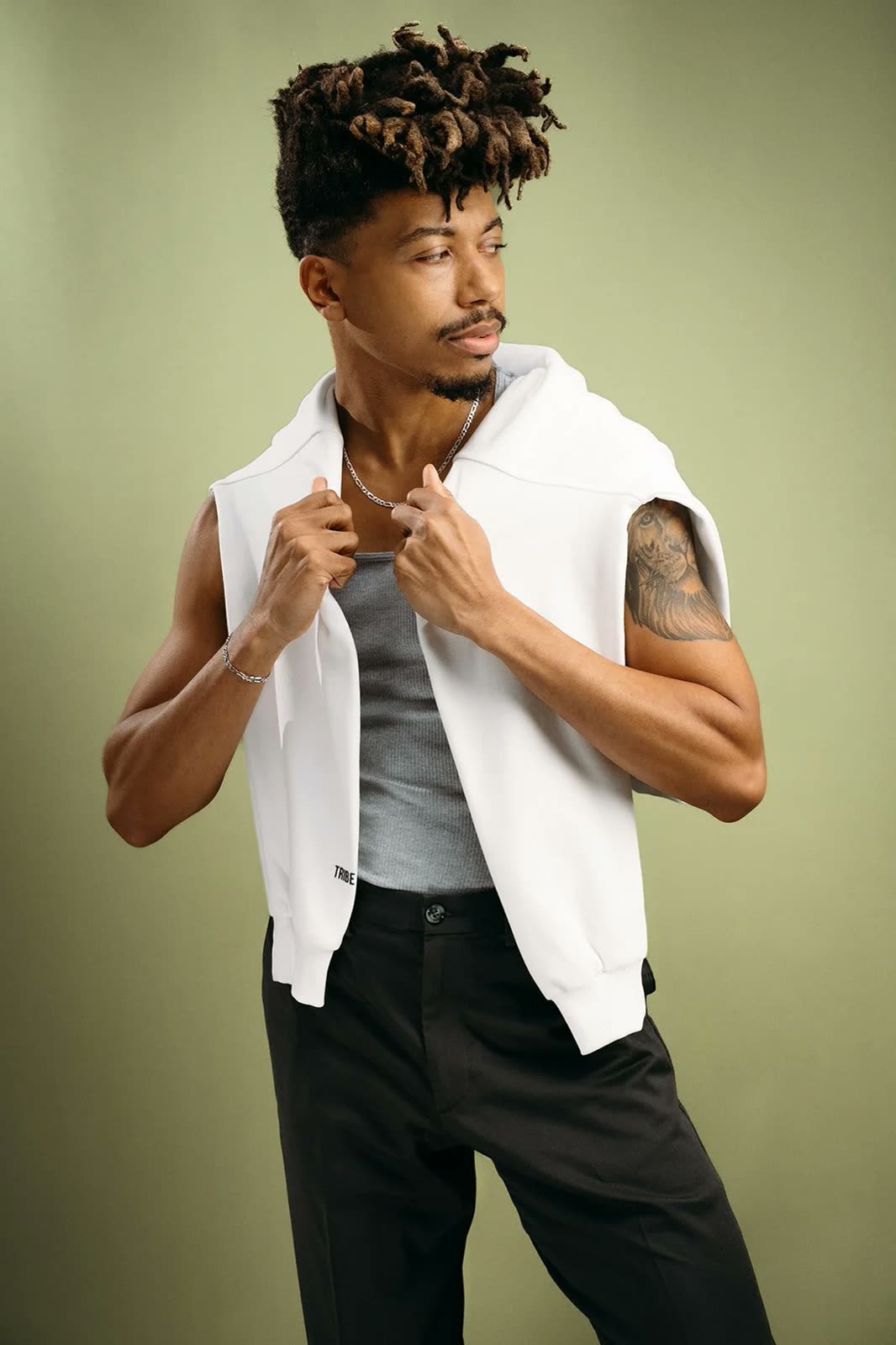Man in a grey tank top with a white hoodie draped over his shoulders