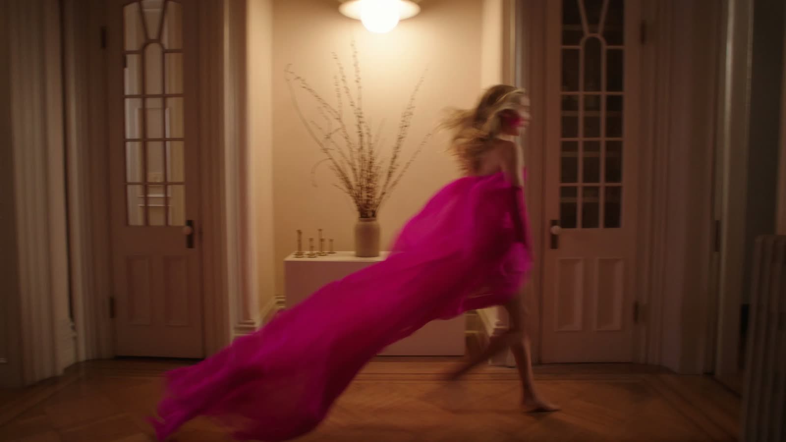 Zoey Deutch runs down a hallway in a flowing hot-pink gown, Estée Lauder film still